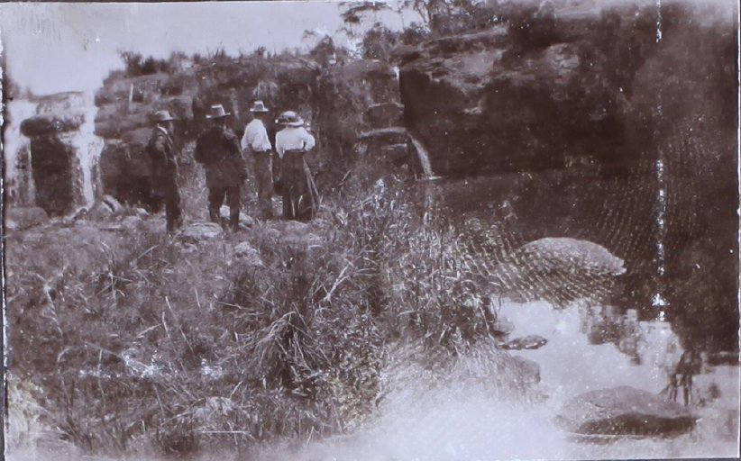 Three men and one woman at a waterfall