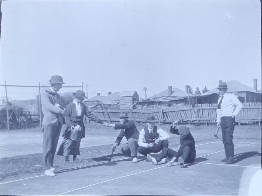 Group of five men and one woman on a tennis court