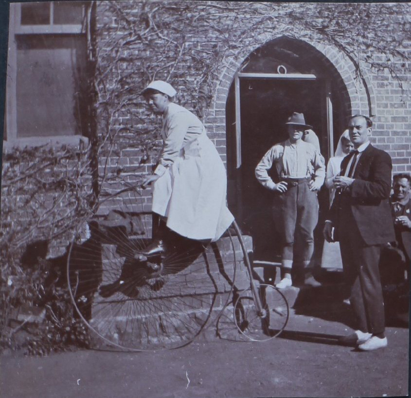 Nurse on a penny farthing outside Booloominbah