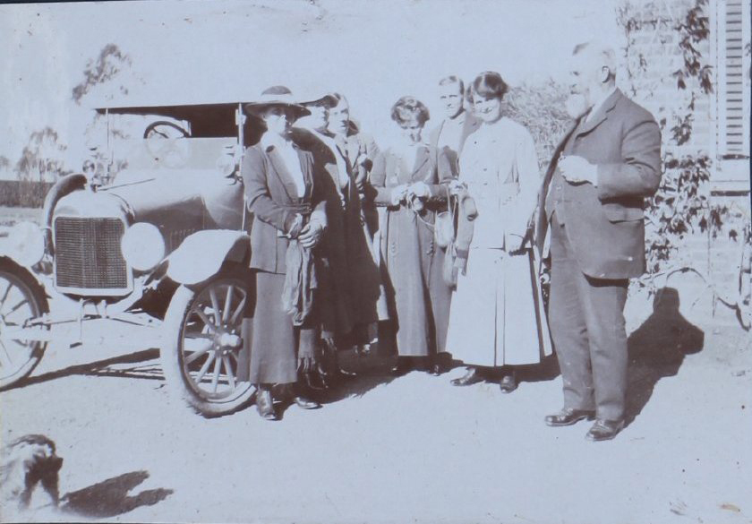Group beside a motor car