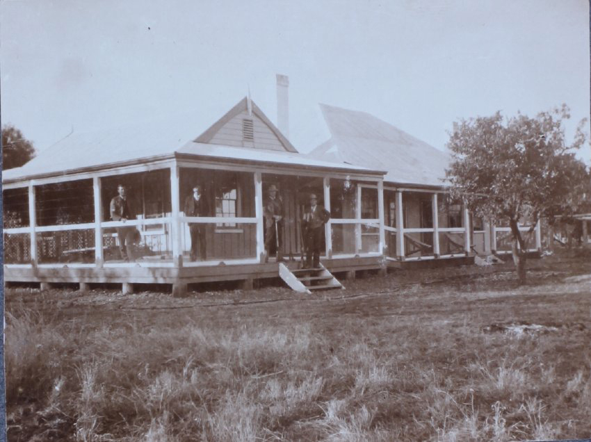 Four gentlemen standing on the verandah of an unidentified residence