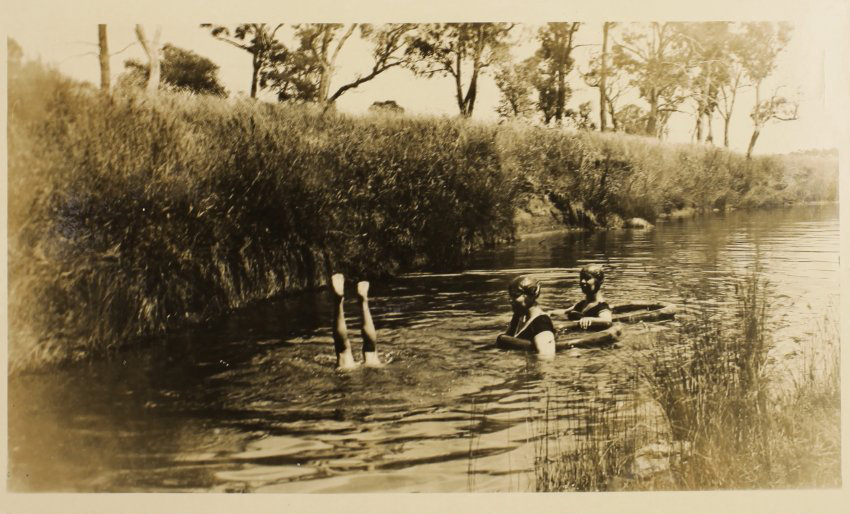 Unidentified woman and two children swimming in the creek
