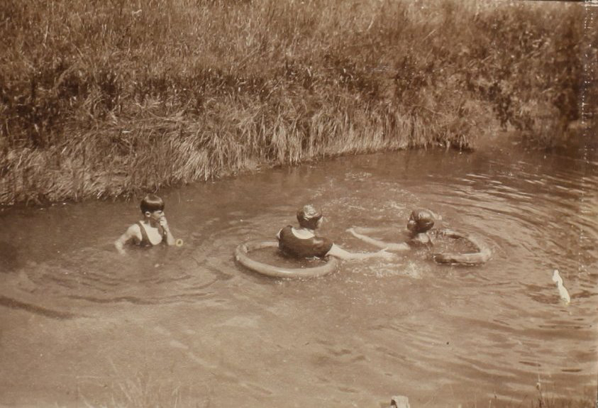 Unidentified woman and two children swimming in the creek