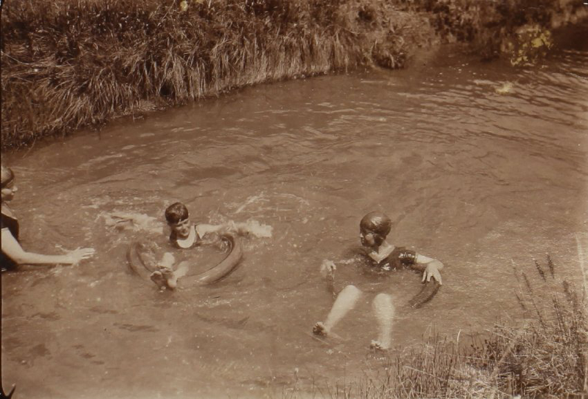 Unidentified woman and two children swimming in the creek