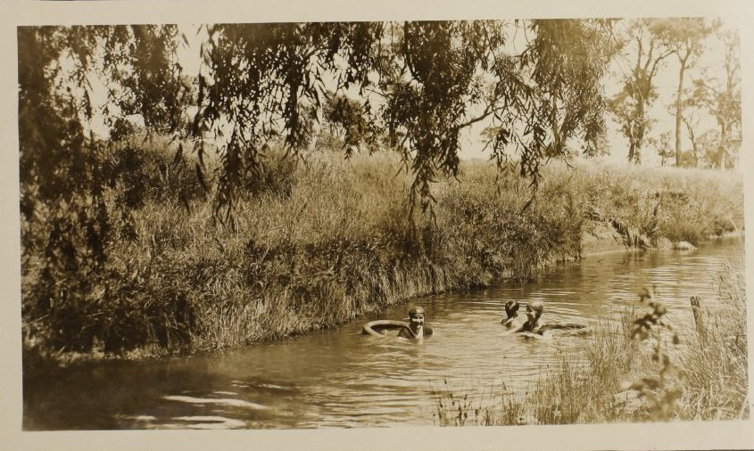 Unidentified woman and two children swimming in the creek