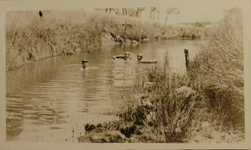 Unidentified woman and two children swimming in the creek