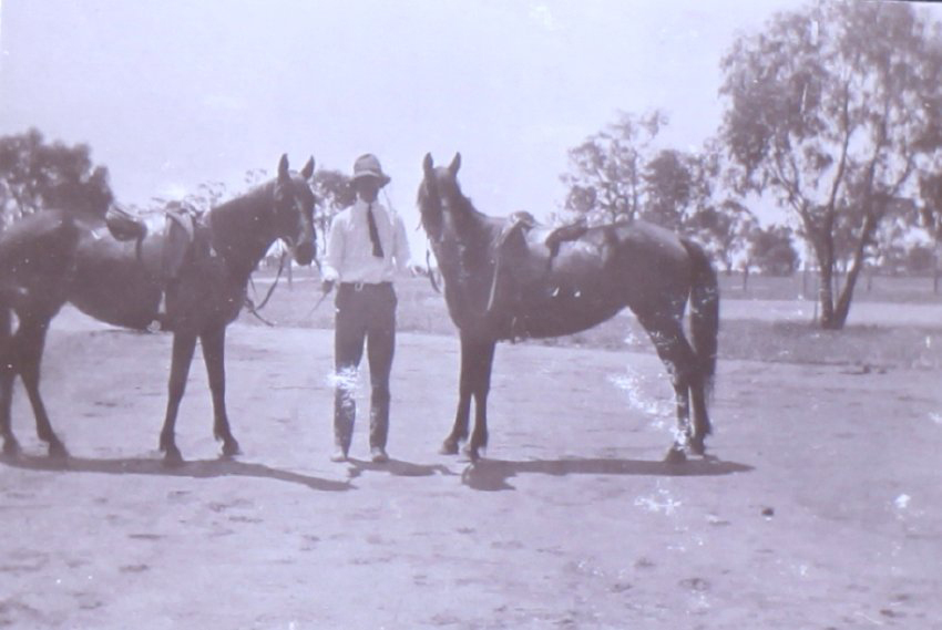 Unidentified man holding two horses