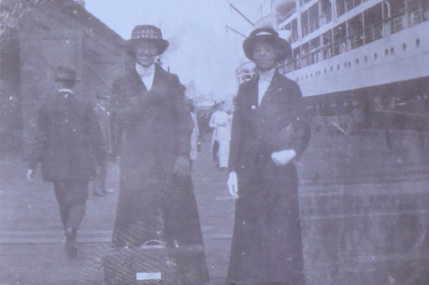 Two unidentified women on the wharf beside a ship