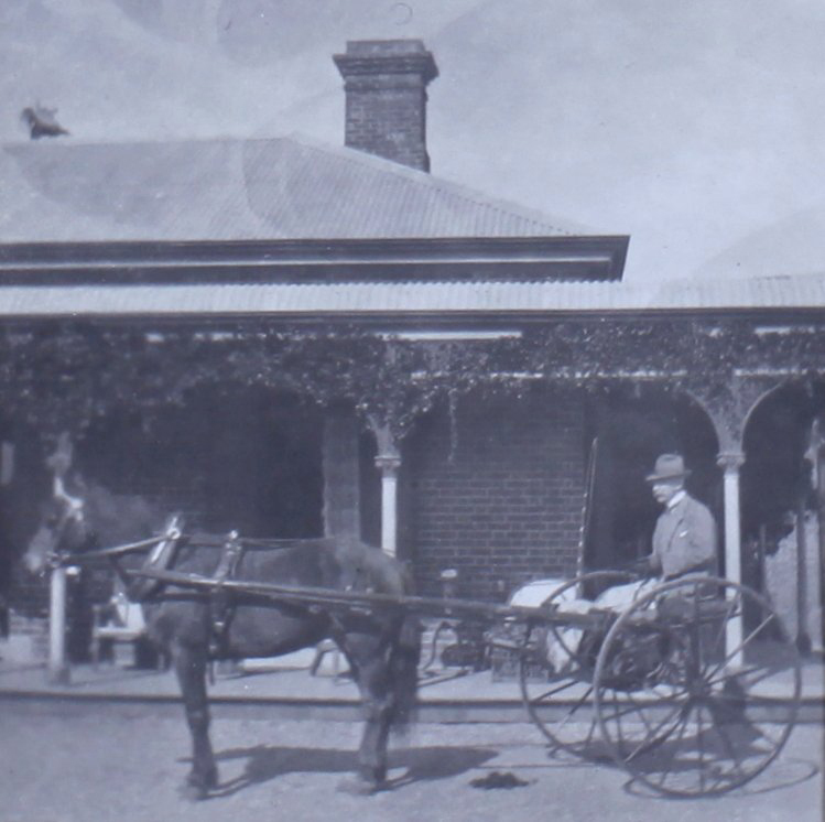 Unidentified man with horse and buggy in front of a house