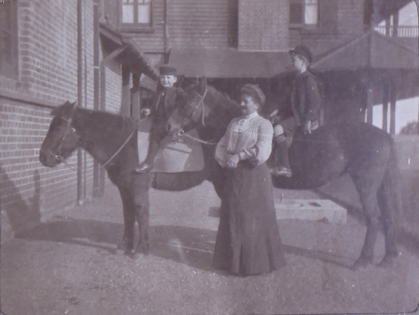 Unidentified woman with two boys on horseback