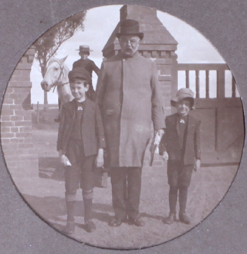 Unidentied man with two boys, another boy in the background on a horse