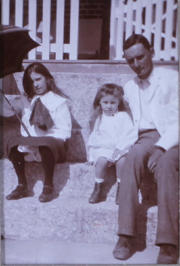 Unidentified man and two girls sitting on steps