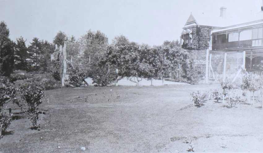 View of gardens, tennis court and house