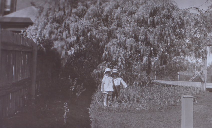 Two unidentified children in the gardens around the tennis court at Saumarez