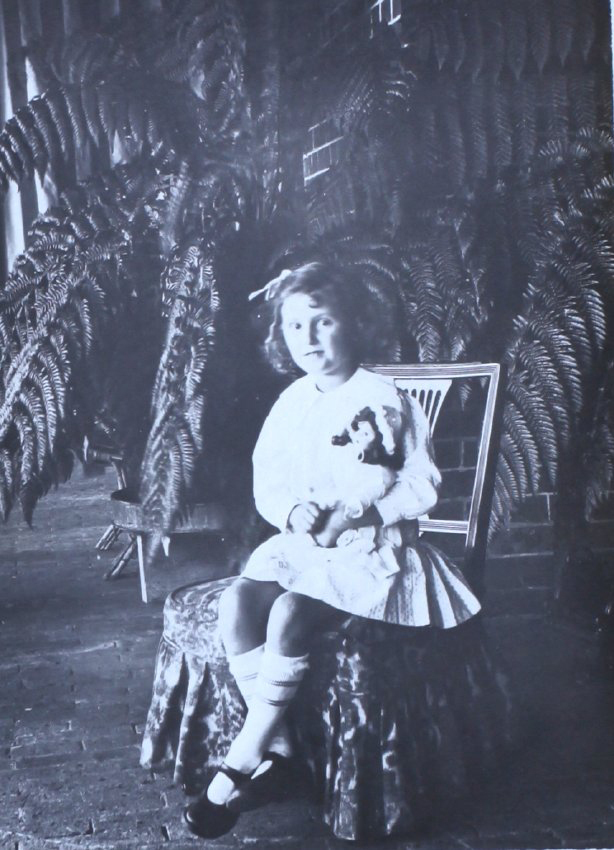Unidentified child sitting in a fernery