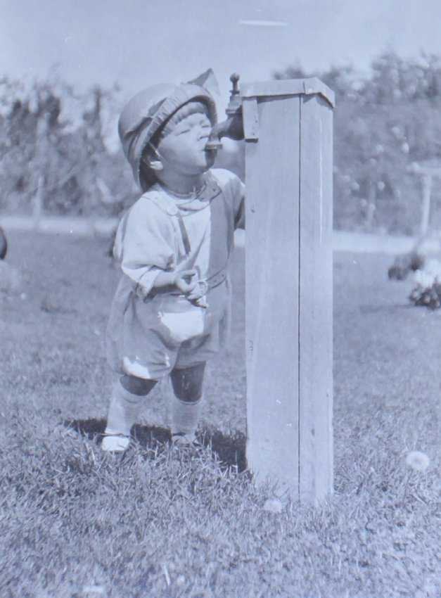 Unidentified boy drinking from a tap