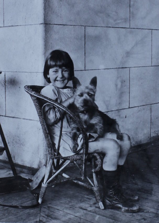 Unidentified girl sitting in a chair with a pet dog
