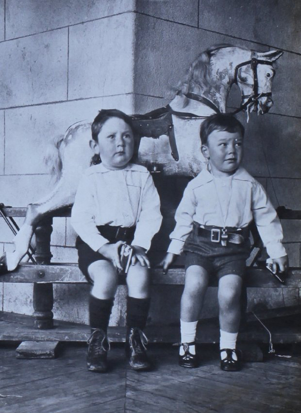 Two young boys sitiing in front of the rocking horse