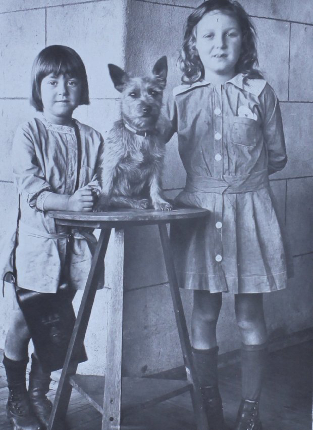 Two young girls standing with a pet dog