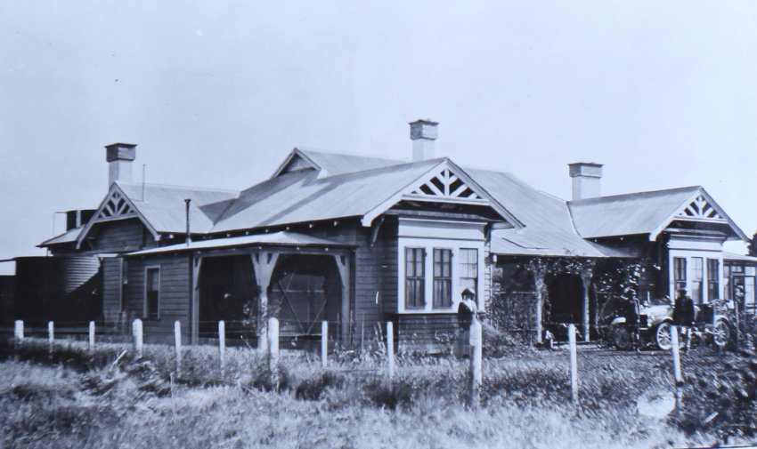 Unidentified house with some people and a car in front