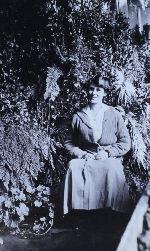 Unidentified woman sitting in a fernery