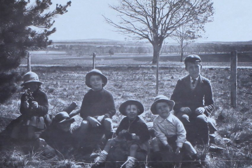 Group of children sitting near a fence