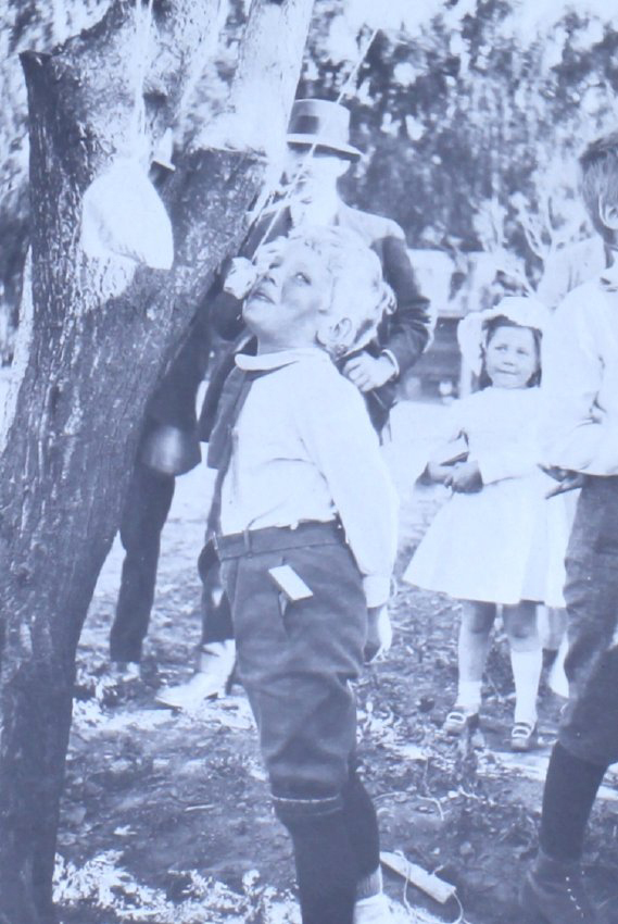 Young boy trying to eat an apple on a string