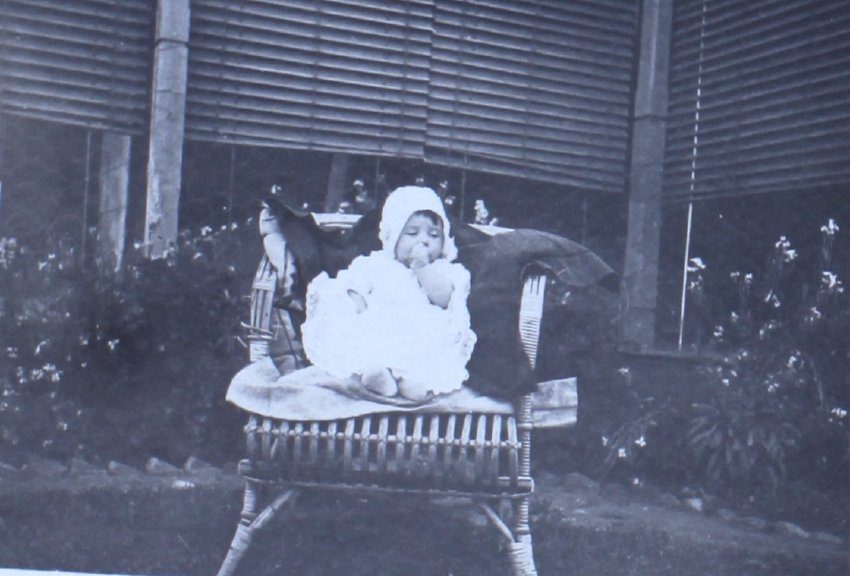 Baby on a cane chair on the lawn