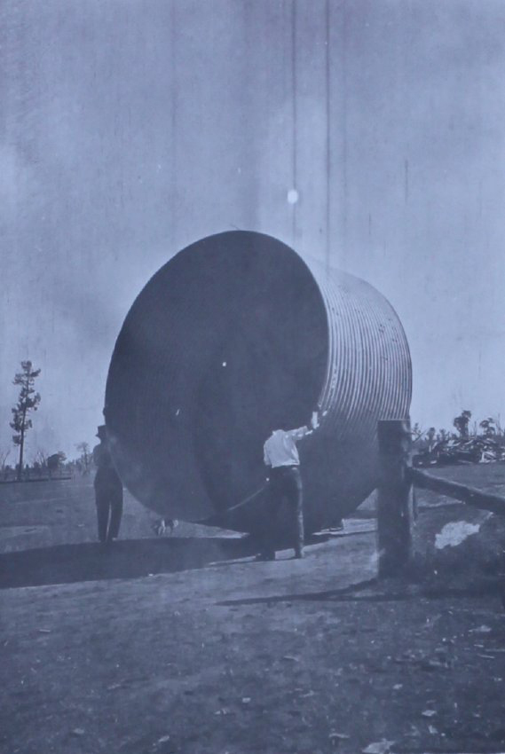 Two men moving a water tank