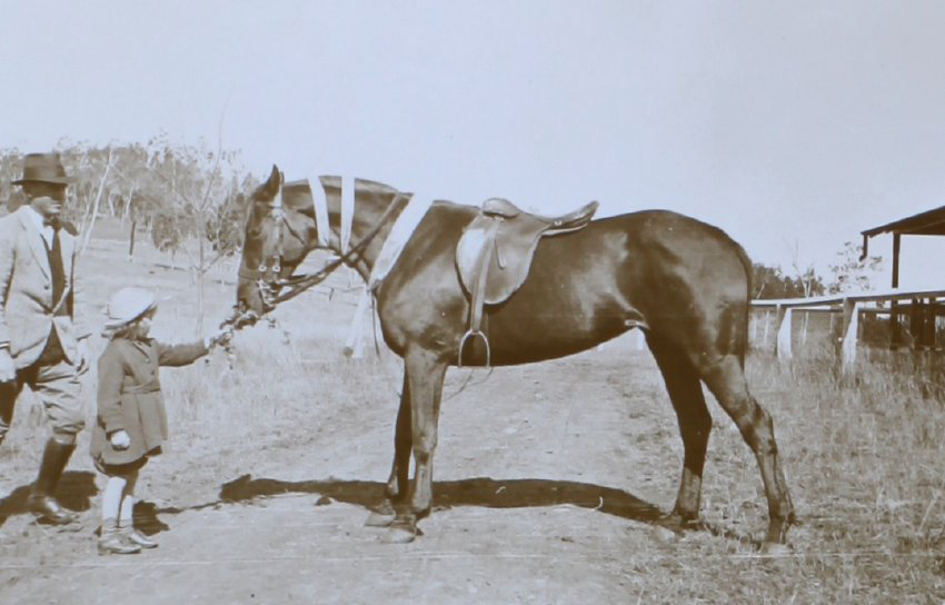 Unidentified man, girl and saddled horse