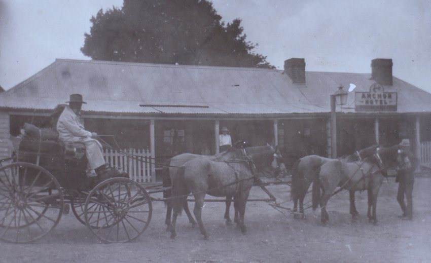 Four horses pulling a buggy in front of the Anchor Hotel