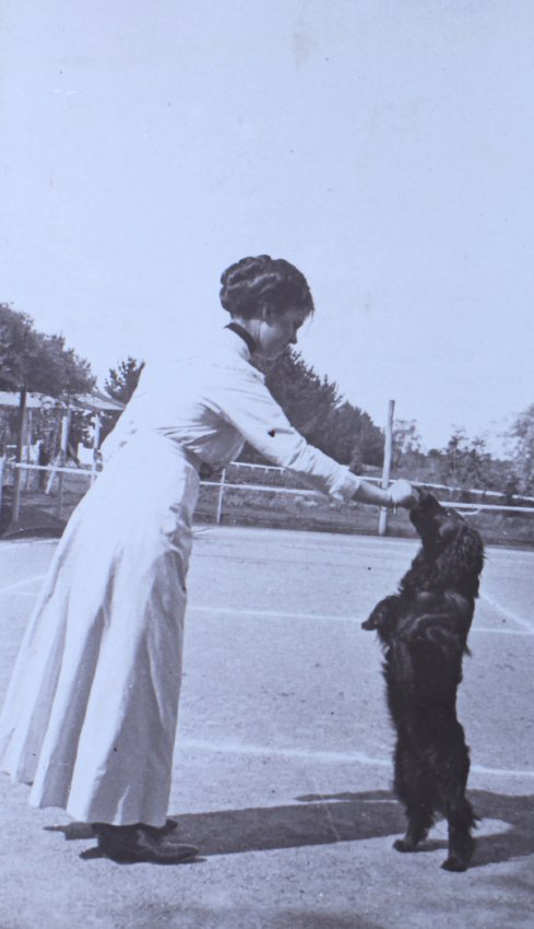 Unidentified woman with pet spaniel in the tennis court