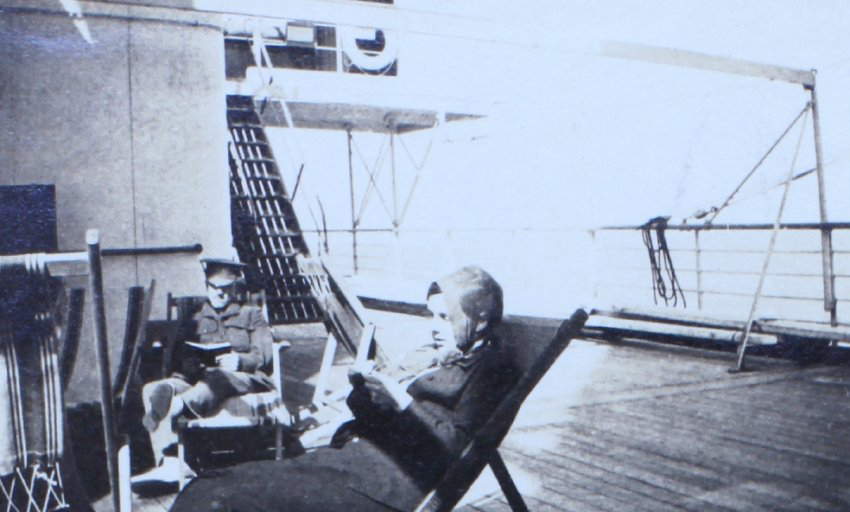 Woman and soldier reading onboard a ship