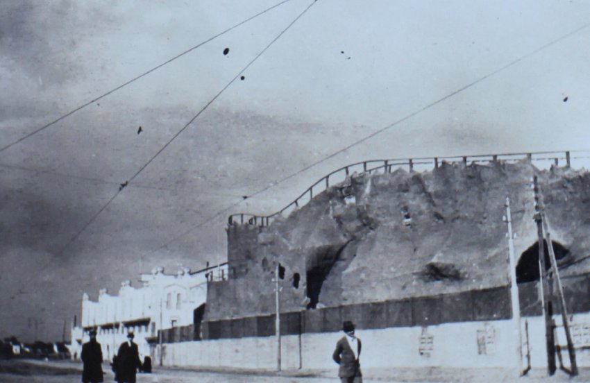 People walking past buildings at the side of a road
