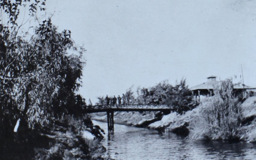 Soldiers on a footbridge over a creek