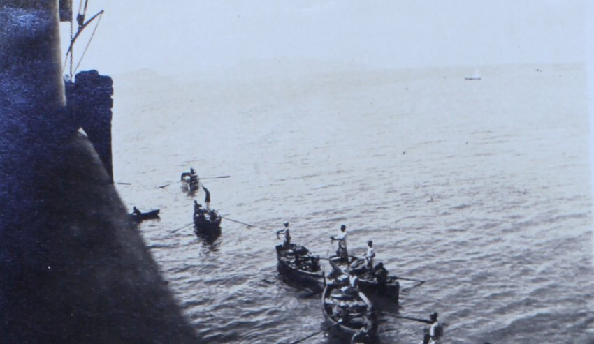 Row boats alongside a troop ship
