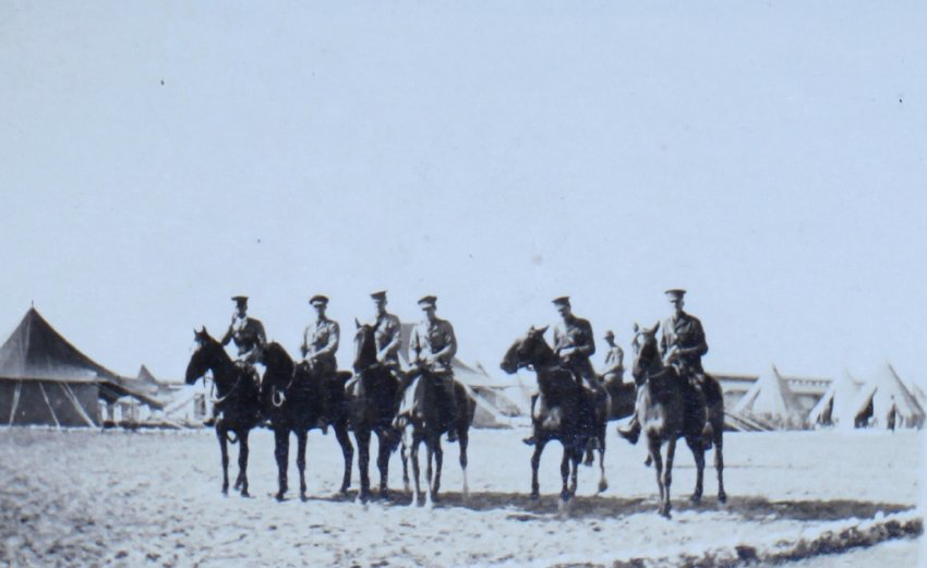 Group of mounted officers with tents in the background