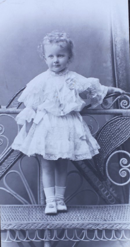 Young girl standing on a cane chair