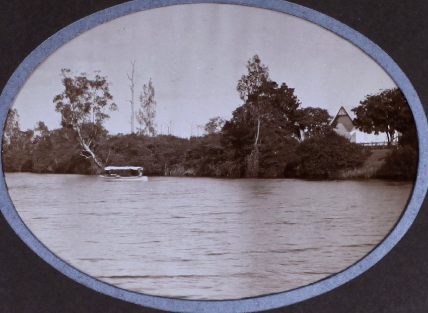 Small boat on a river with a house on the far bank