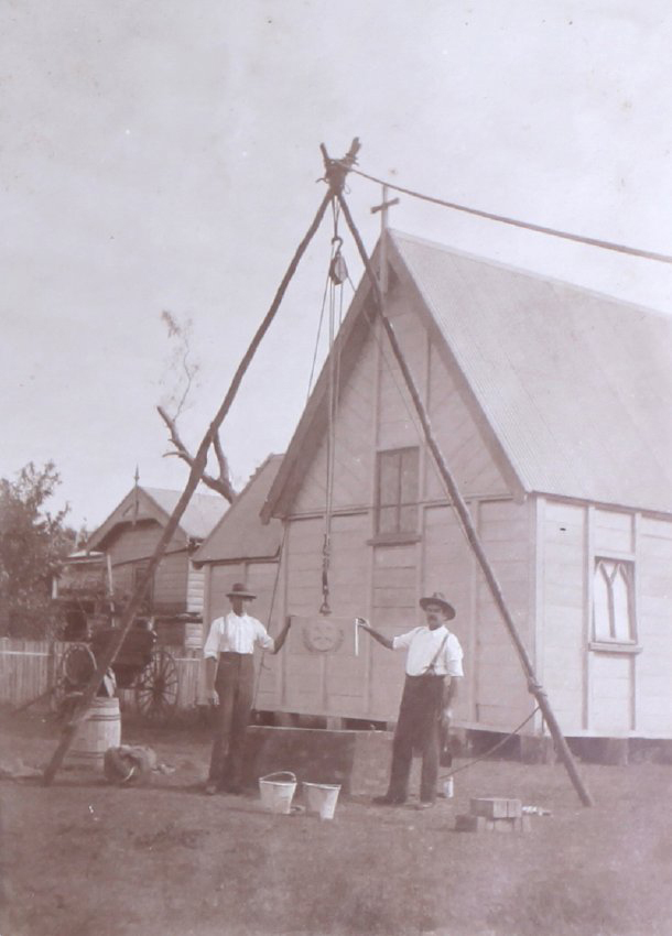 Two men setting a foundation stone in place for a small church