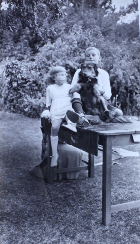 Boy and a girl sitting on a table with a pet dog