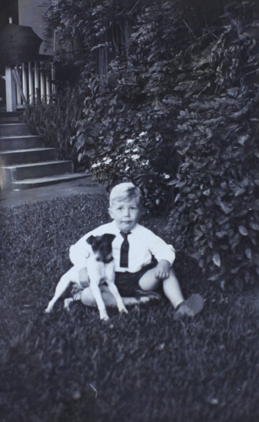 Young boy sitiing on the grass with a pet dog