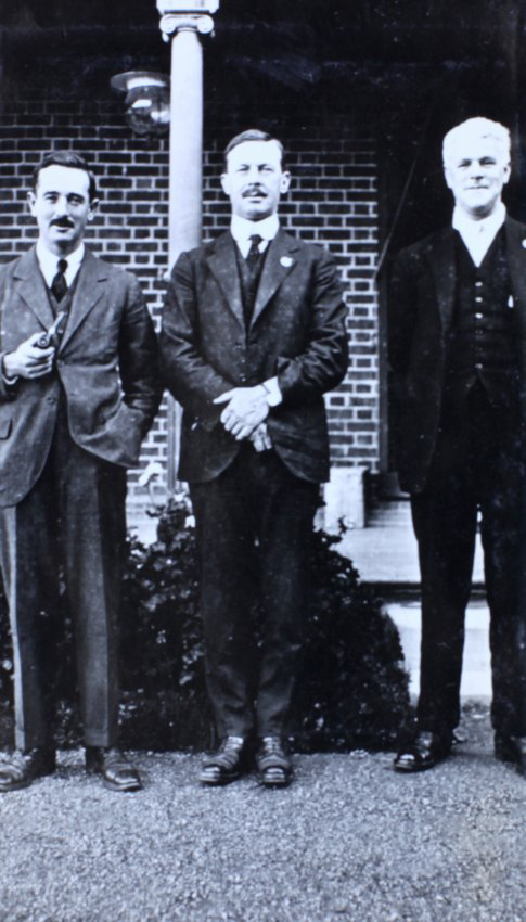 Three men standing in front of a house