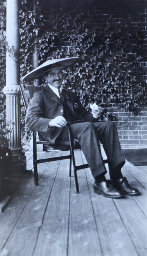 Man sitting on the verandah wearing an Asian style hat