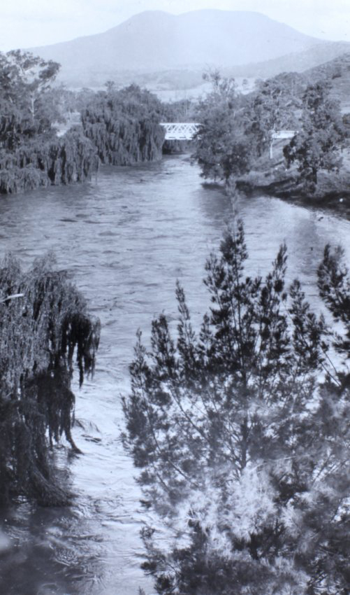 Looking down a flooded river to a bridge