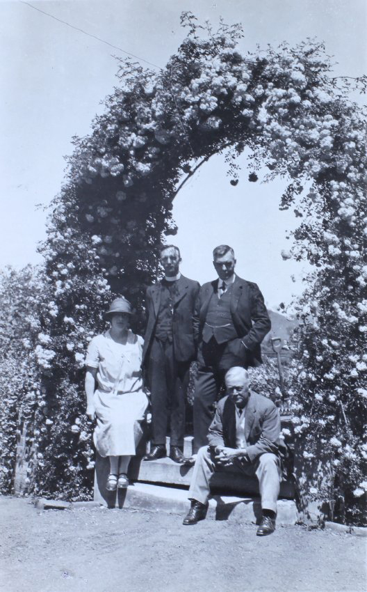 Three unidentified man and a woman under a garden arch