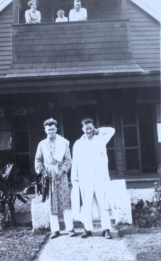 Two unidentified men in pyjamas standing in front of a house