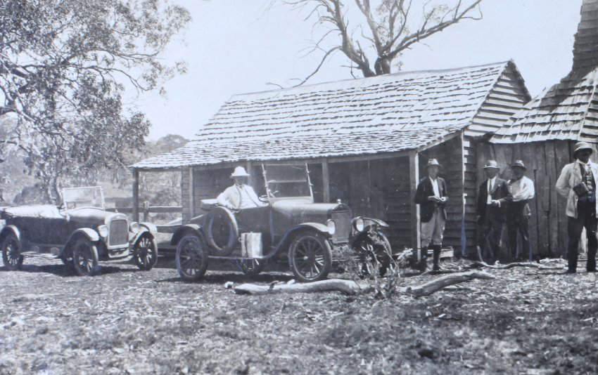 Group of men standing outside a bush hut