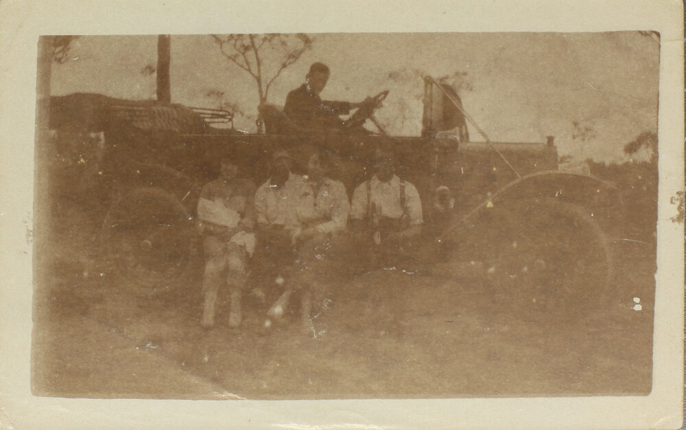 Family sitting on runningboard of motor car