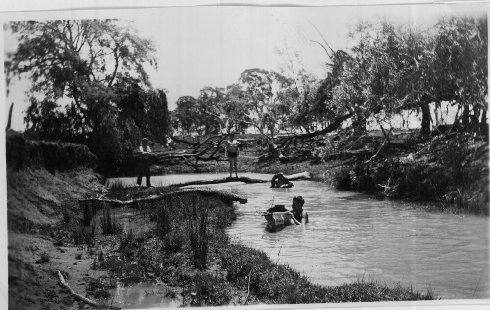 Young boys swimming in the creek with tin canoe
